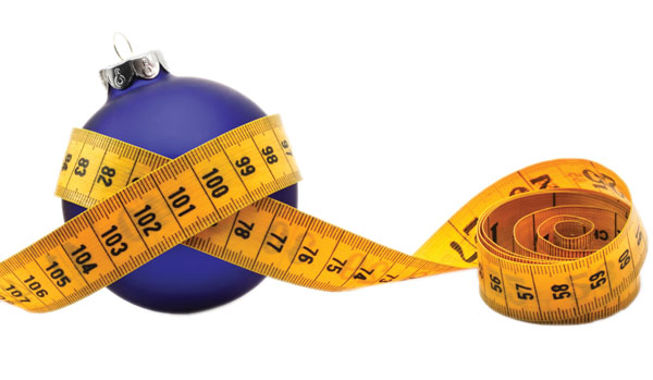 Tape measure around a bauble concept symbolizing Christmas weight gain from eating too much food.