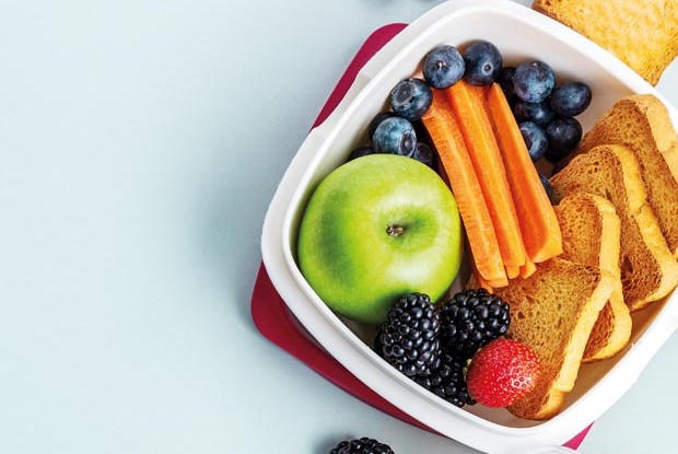Healthy lunch to go. Fruits and vegetables packed in lunch box. Healthy eating concept. View from above with copy space.