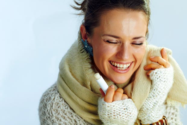 happy stylish middle age woman with lip balm as winter lip care