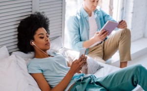 Relaxing woman listening to music on phone while man reading boo