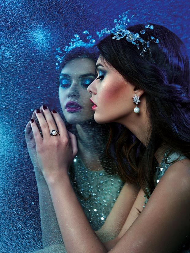 beautiful young girl in pearl jewelry looks at her reflection in