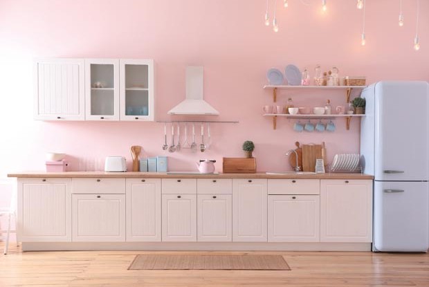 Stylish pink kitchen interior with modern furniture and fridge