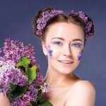 Beautiful young girl is surrounded by purple flowers. Pretty nic