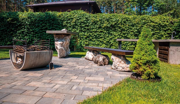 Iron fire pit with benches on stone pavement in garden backyard